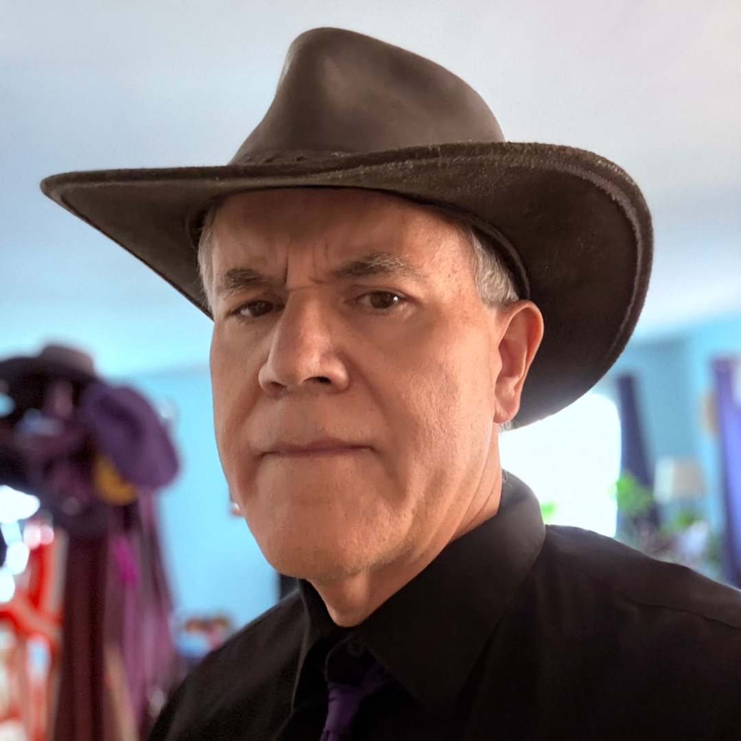 A portrait if this site's author, Bruce H. McCosar. Has that rugged look of someone who's spent all day typing on a laptop. Also wearing one of his trademark black hats, a black shirt, and a dark purple tie.